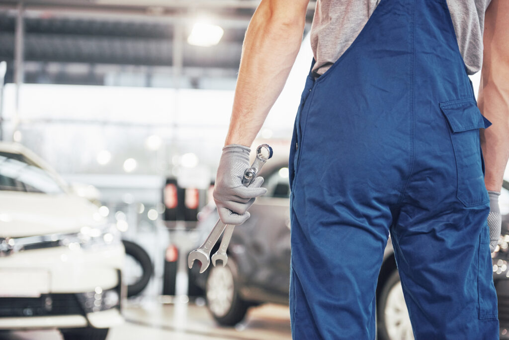 Hands of car mechanic with wrench in garage.